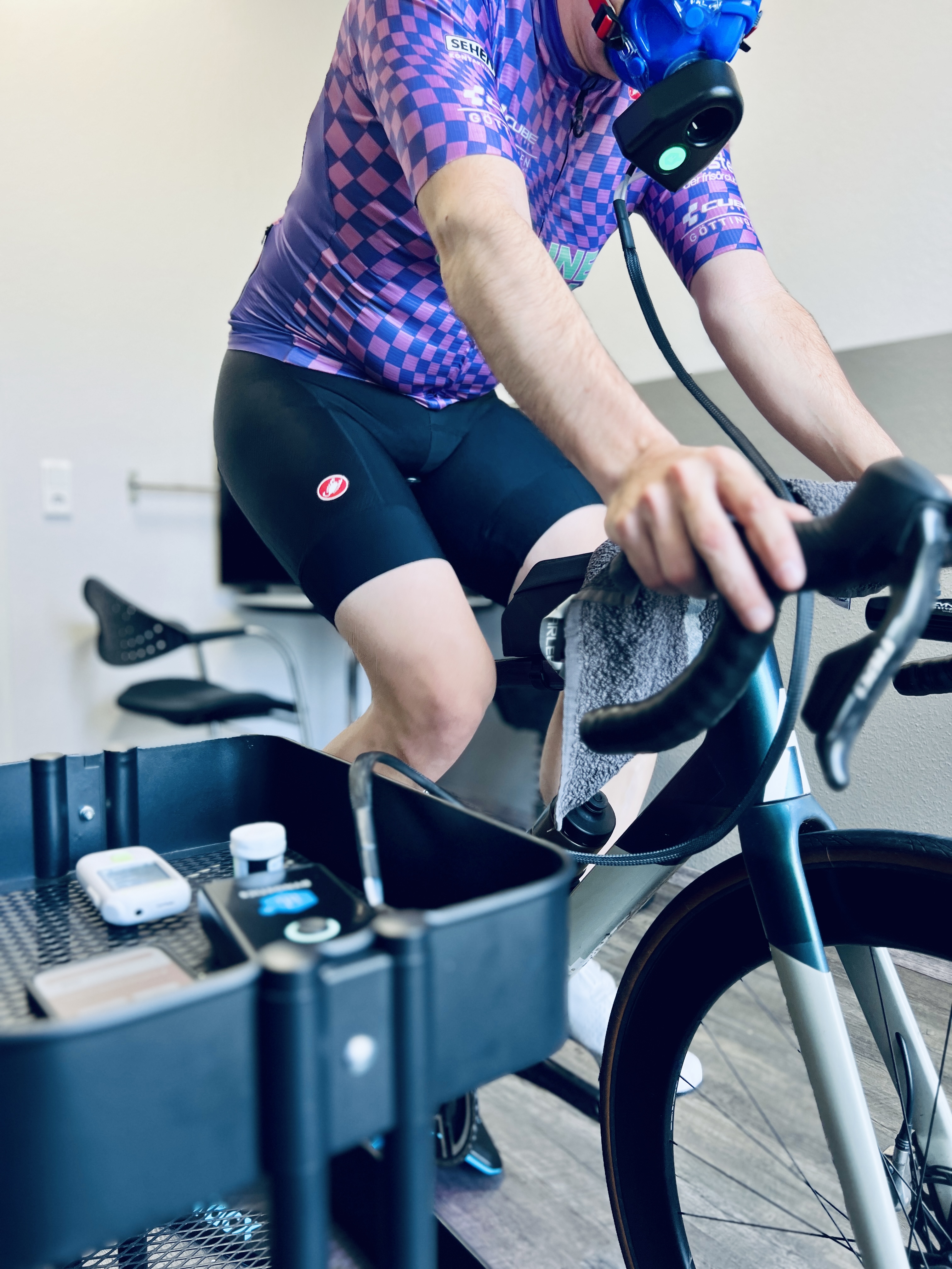 Sportler mit Atemmaske während einer Leistungsdiagnostik auf dem Rennrad
